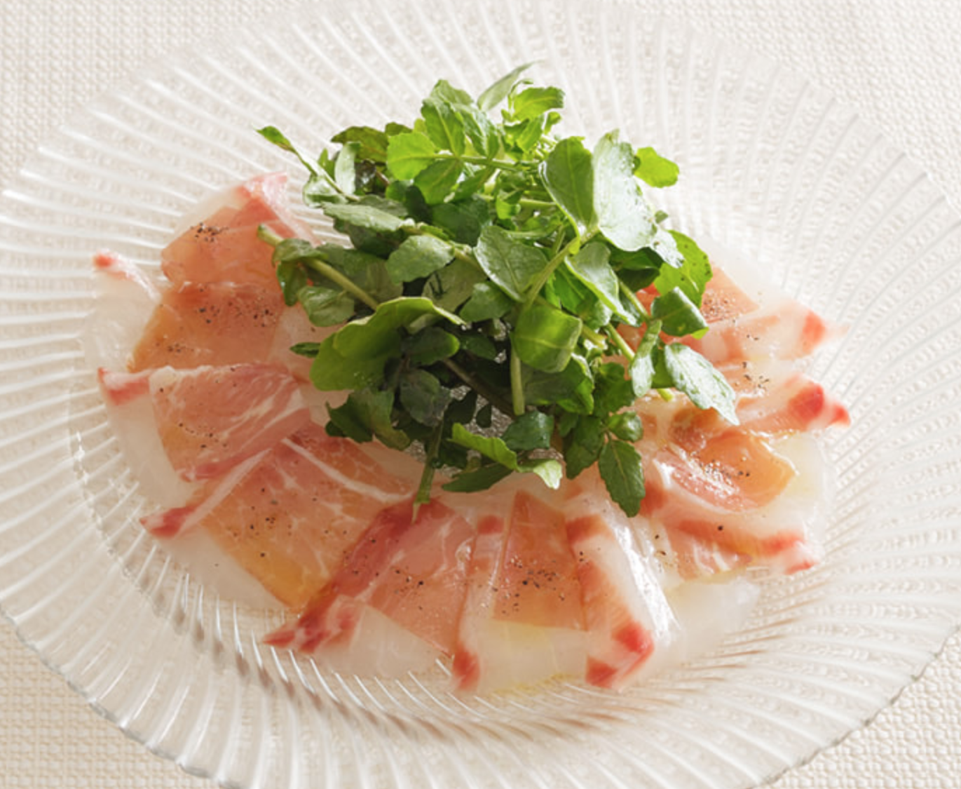 Carpaccio de dorada y jamón curado con rucula y patatas especiadas.